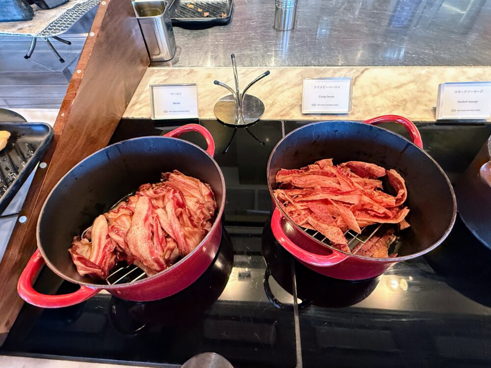 赤い鋳物ホーロー鍋にたっぷり用意されたベーコンと、カリッと焼かれたクリスピーベーコン。