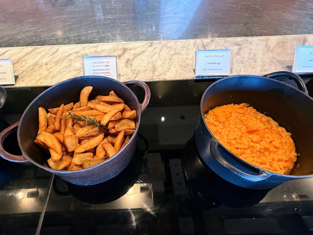 黒い鍋に入った「ごろごろポテトのローズマリー風味」と、色鮮やかな「スクランブルエッグ」。
