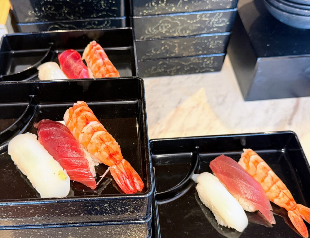 黒いお重のような器に盛り付けられた、マグロ、イカ、エビの握り寿司。ツヤツヤで新鮮な様子が伝わる。