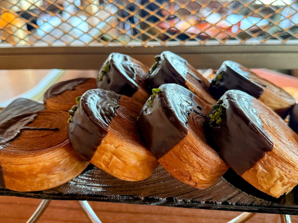 チョコレートがコーティングされ、グリーンのピスタチオがアクセントに乗った丸い渦巻き状のデニッシュパン。