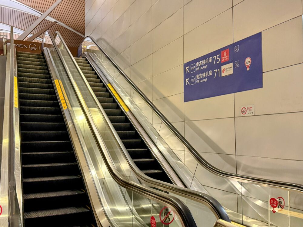 上海浦東国際空港のエスカレーター脇の壁面案内板。No.75(エミレーツ)とNo.71(エアチャイナ)VIPラウンジへの方向が示されている。