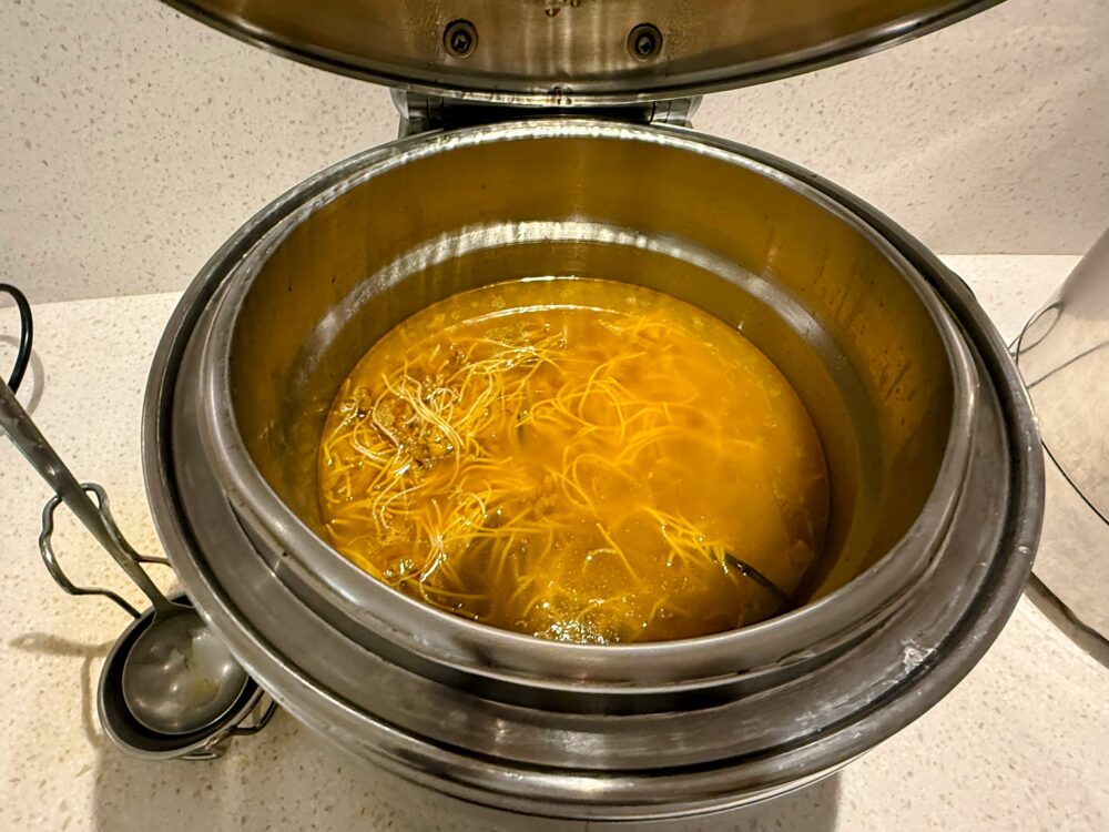 No.71ラウンジビュッフェのスープ保温容器。黄金色のスープに細麺が浮かぶ。