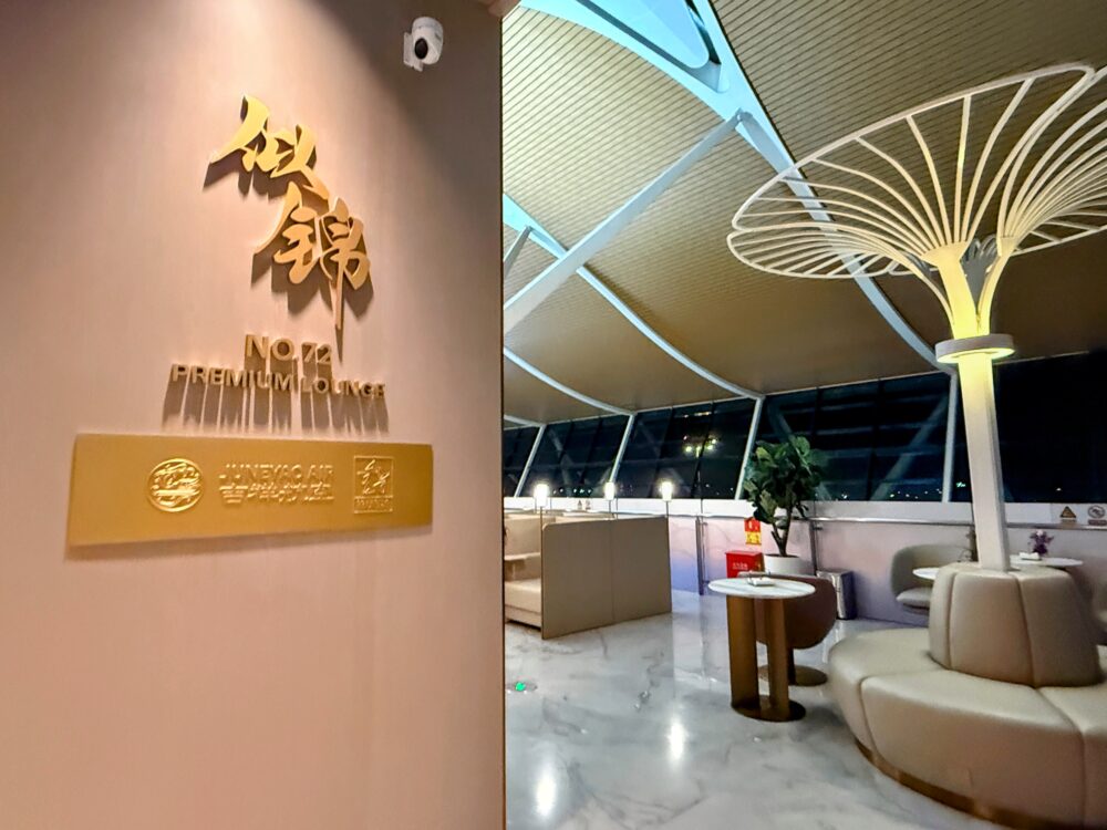 No.72吉祥航空ラウンジの入口。金色の立体文字「焱錦 No.72 Premium Lounge」と吉祥航空のロゴが壁に輝く。奥に白い木をモチーフにしたオブジェと大型ガラス窓越しの夜景が広がる。