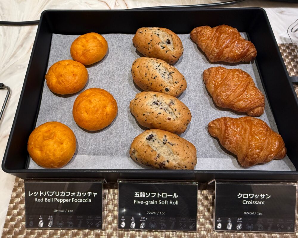 ビュッフェのパンコーナー。左からレッドパプリカフォカッチャ、五穀ソフトロール、クロワッサンの3種が黒いトレイに並ぶ。