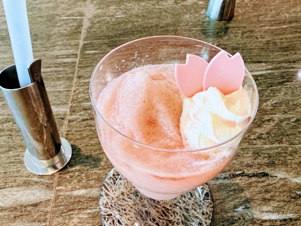 桜シロップ・桜ジャム・アセロラジュースを丸ごとブレンドした春色のフローズンドリンク「ANA Ice Magic」。桜型チョコレートが添えられた愛らしい見た目も魅力。