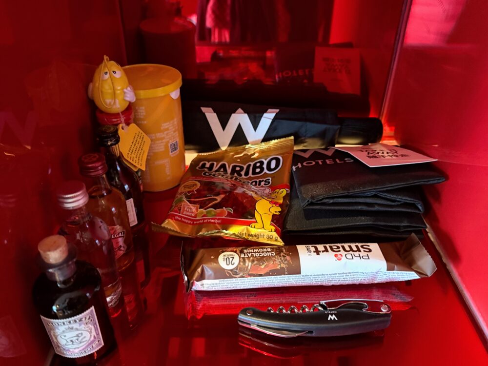ハ。リボーのグミやミニボトルのお酒、Wロゴ入りの折りたたみ傘などのミニバーアイテム