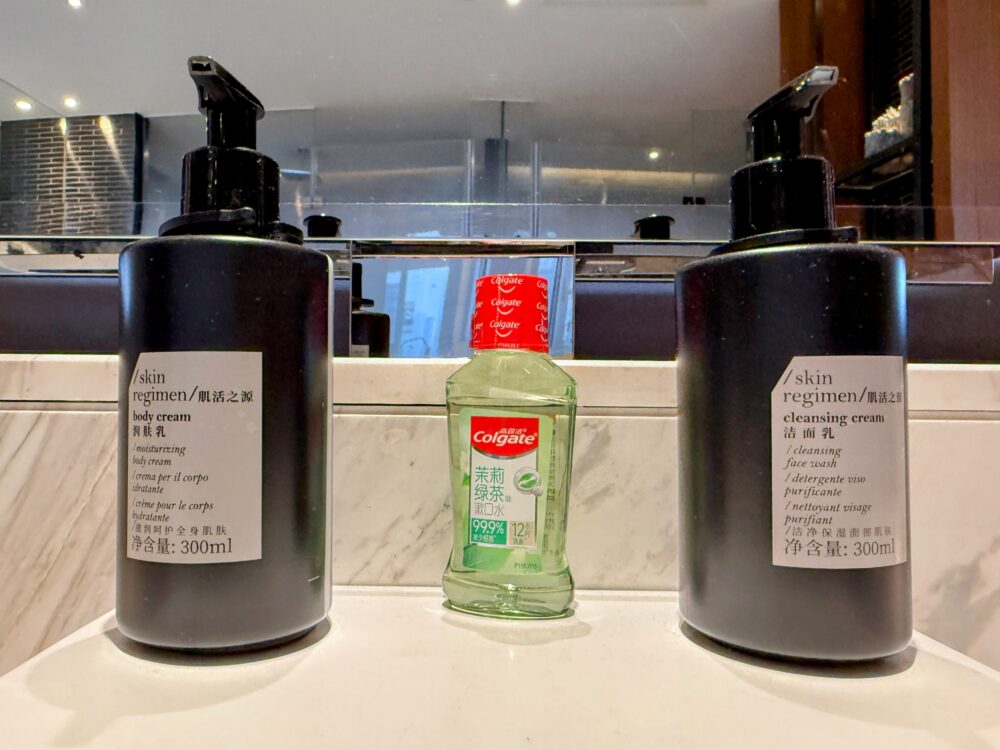 洗面台に用意された「skin regimen(スキンレギメン)」のボディクリームとクレンジングクリーム、中央に置かれたコルゲートのマウスウォッシュ。