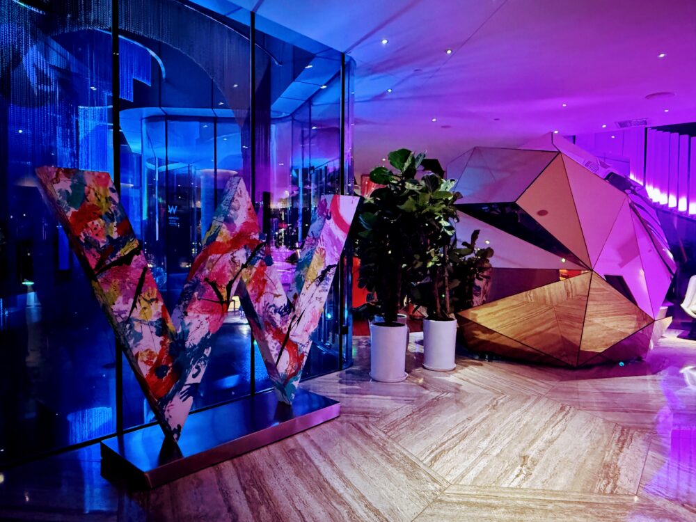 カラフルなペイントが施されたポップな「W」のモニュメントとスタイリッシュな館内(夜)