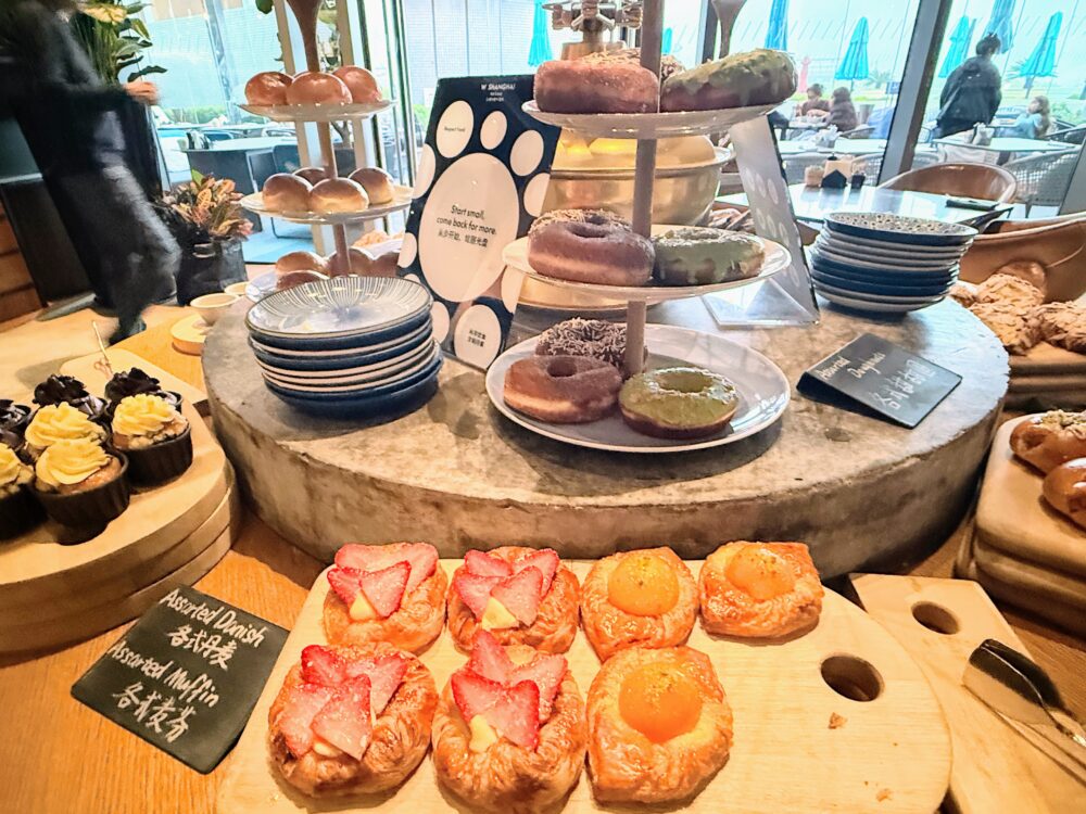 W上海「THE KITCHEN TABLE」朝食ビュッフェのデザートコーナー。カラフルなドーナツが3段スタンドに積まれ、アソーテッドデニッシュやマフィンも並ぶ。