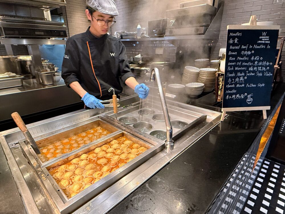 朝食ビュッフェのライブキッチン。湯気が立ち上るヌードルステーションで麺を茹でるシェフの様子。