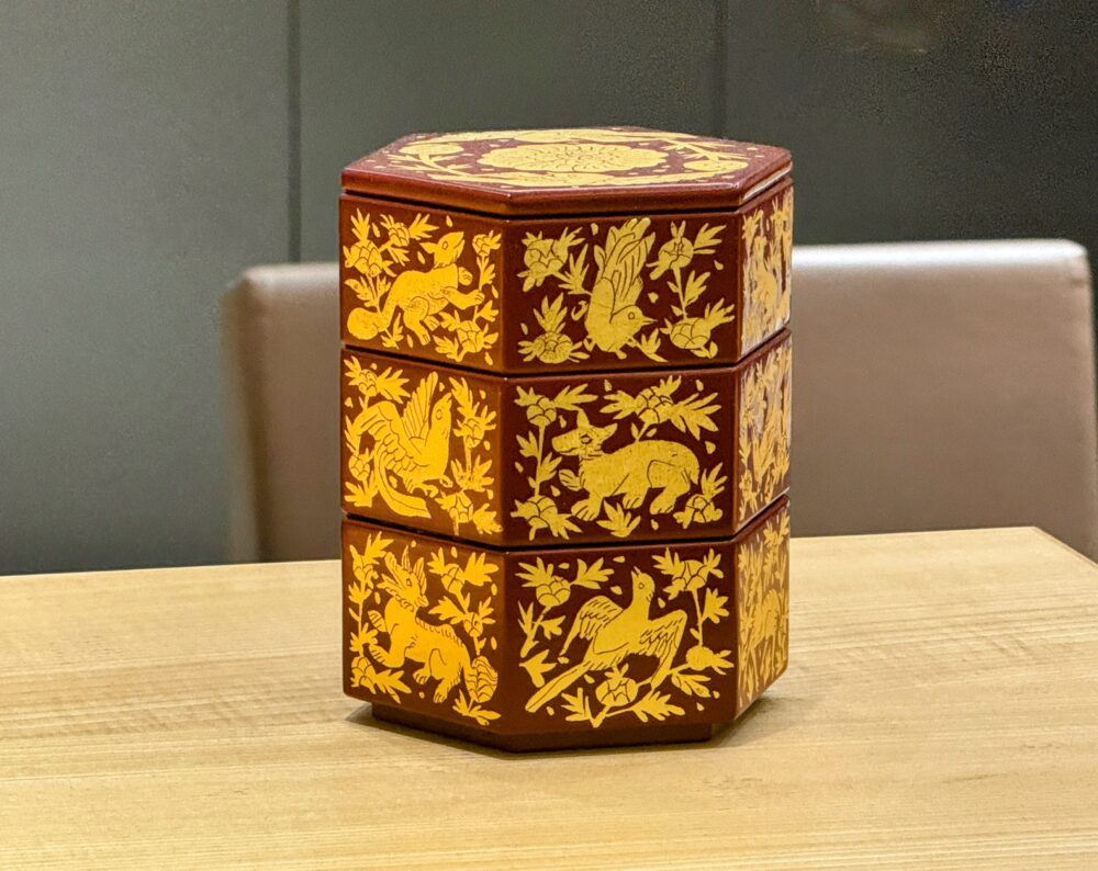 伝統的な鳥や獣の箔絵が美しく描かれた六角形の琉球漆器の重箱。