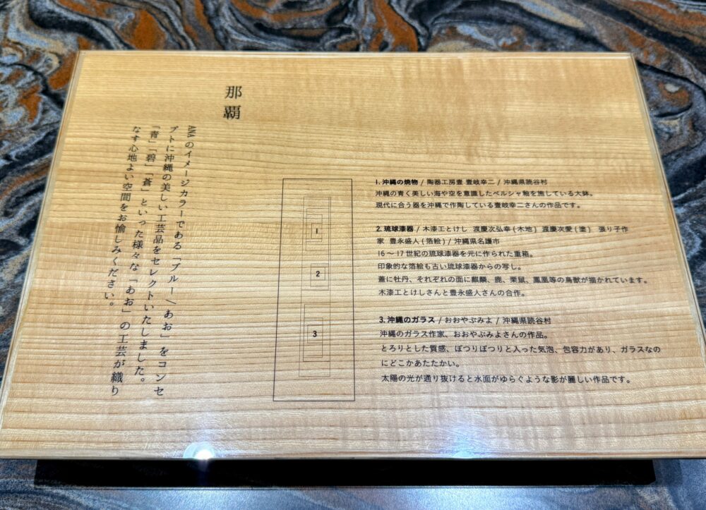 ラウンジ内に展示されている沖縄の伝統工芸品（焼き物、漆器、ガラス）のコンセプトと説明書き。