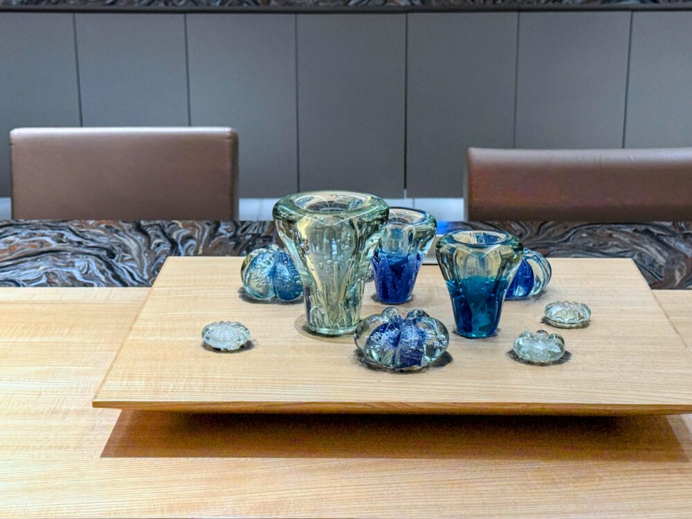 中央の大テーブルに飾られた、光を反射して輝く気泡が美しい沖縄の工芸品「琉球ガラス」のアップ写真。