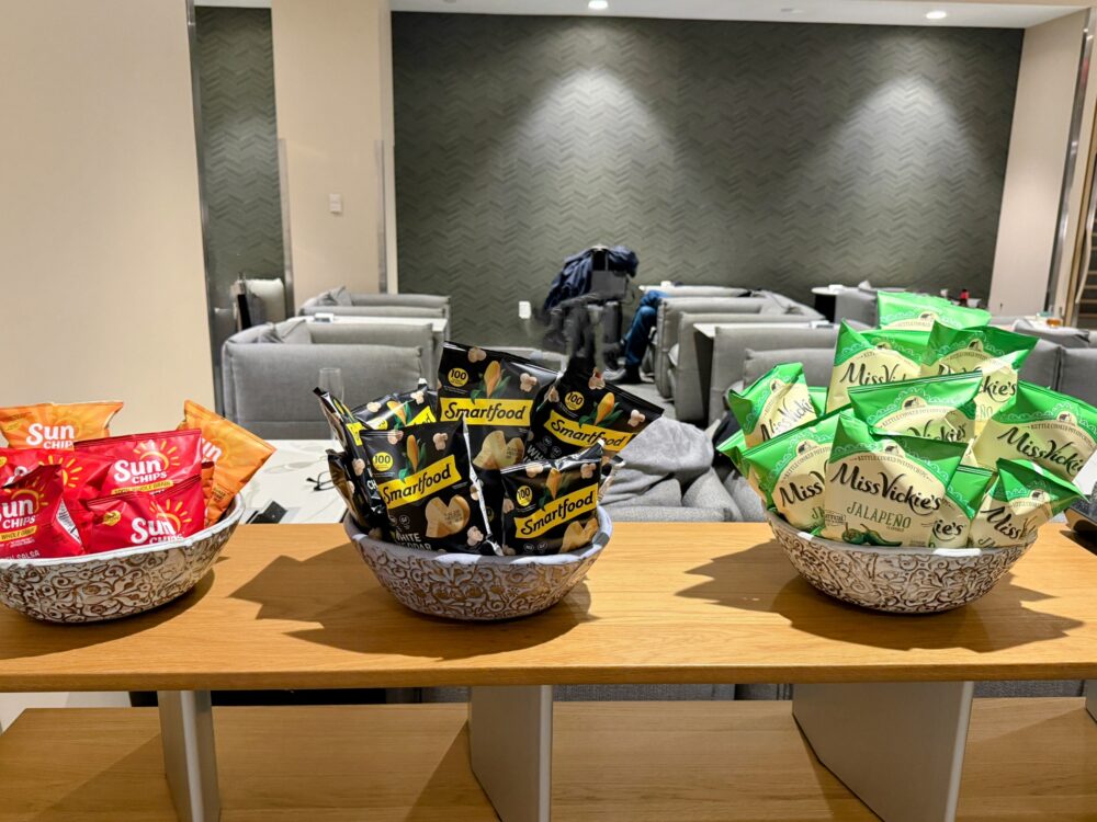 ファーストクラスラウンジのスナックコーナー。Sun Chips、Smartfood、Miss Vickie'sのポテトチップスがボウルに入って3種並んでいます。