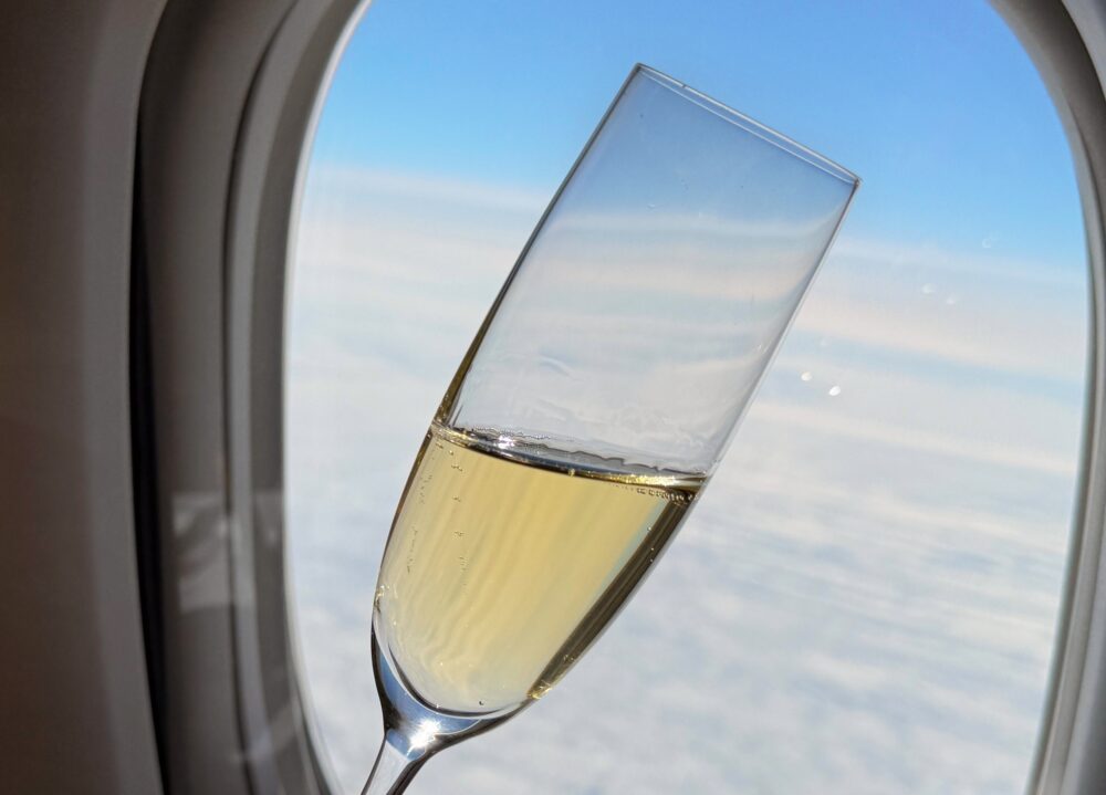 飛行機の窓から見える青空と美しい雲海を背景にしたシャンパングラス。