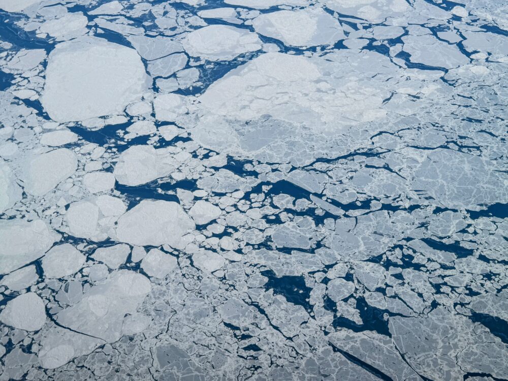 北極海の上空から撮影した、海面に浮かぶ壮大な流氷と青い海。