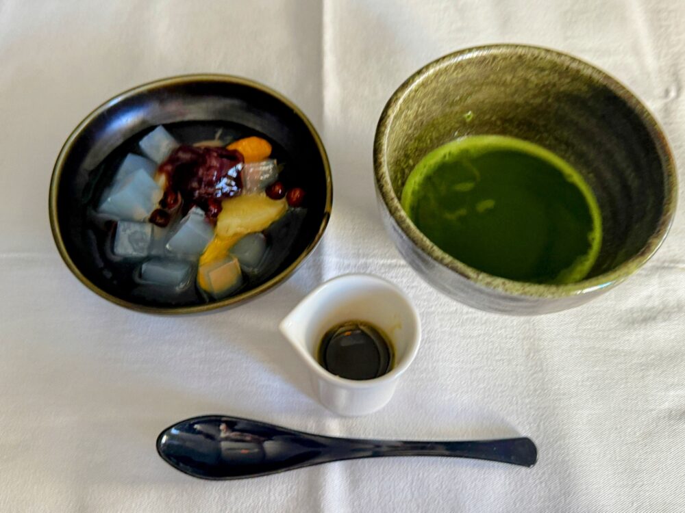 食後のデザート。和菓子屋のあんみつ(抹茶みつ)と、機内で点てられた温かいお抹茶。