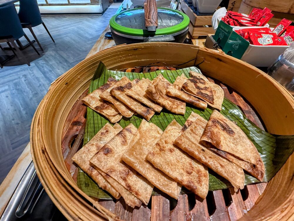 シルバークリスラウンジの木製蒸籠(せいろ)に入れられた、バナナの葉の上に並ぶ薄焼きパン(チャパティ)。