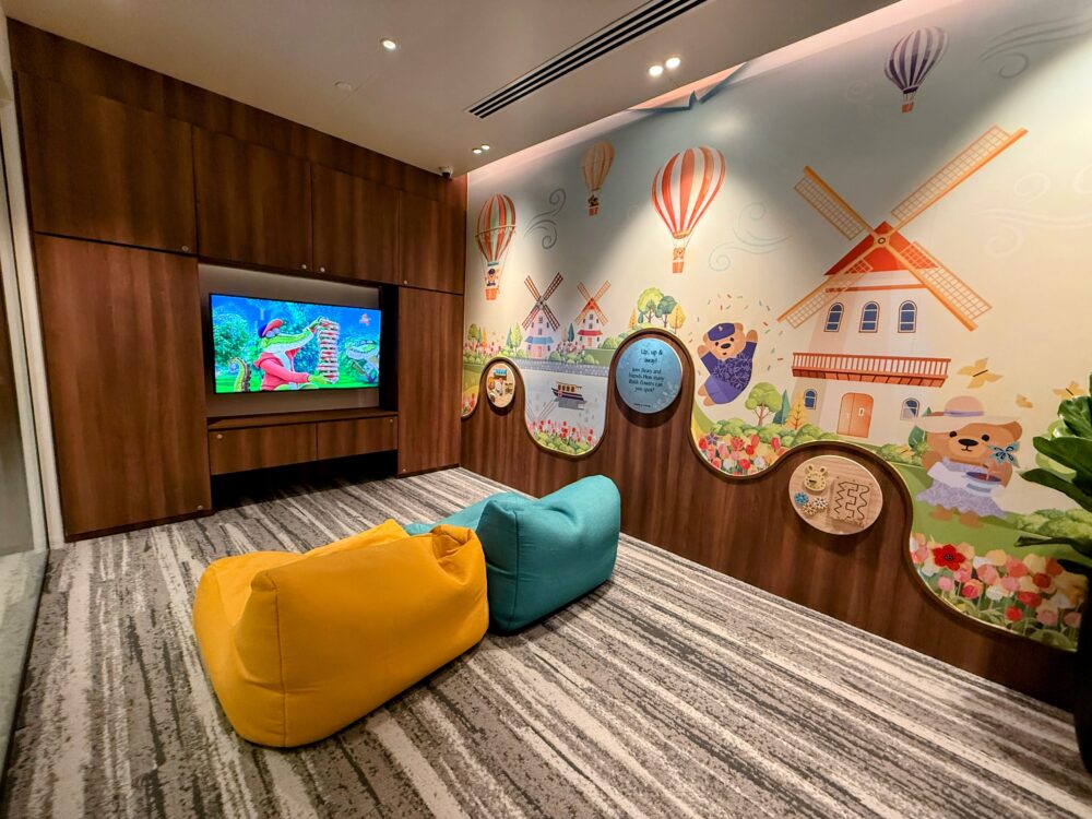 子供向けの可愛らしい壁画、テレビ、ビーズクッションが配置されたキッズルーム(プレイルーム)。