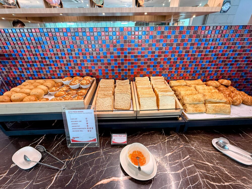 SATSプレミアラウンジのベーカリーコーナーに並ぶ焼き立てのパンやマフィン、横にはジャム類。