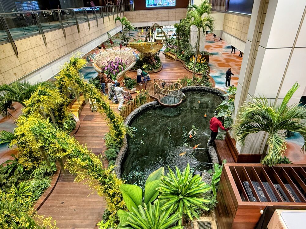 シンガポール・チャンギ空港第2ターミナルの『Enchanted Garden』を見下ろした様子。蘭の花や緑豊かな庭園と中央の池があるこの素晴らしい空間の上に、ラウンジが位置しています