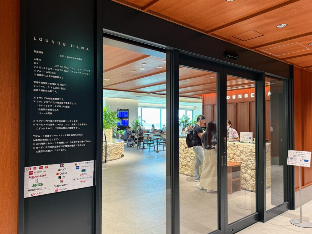 那覇空港カードラウンジ「LOUNGE HANA」の入口看板と営業時間・入場料・対応カード一覧が記載されたサインボード