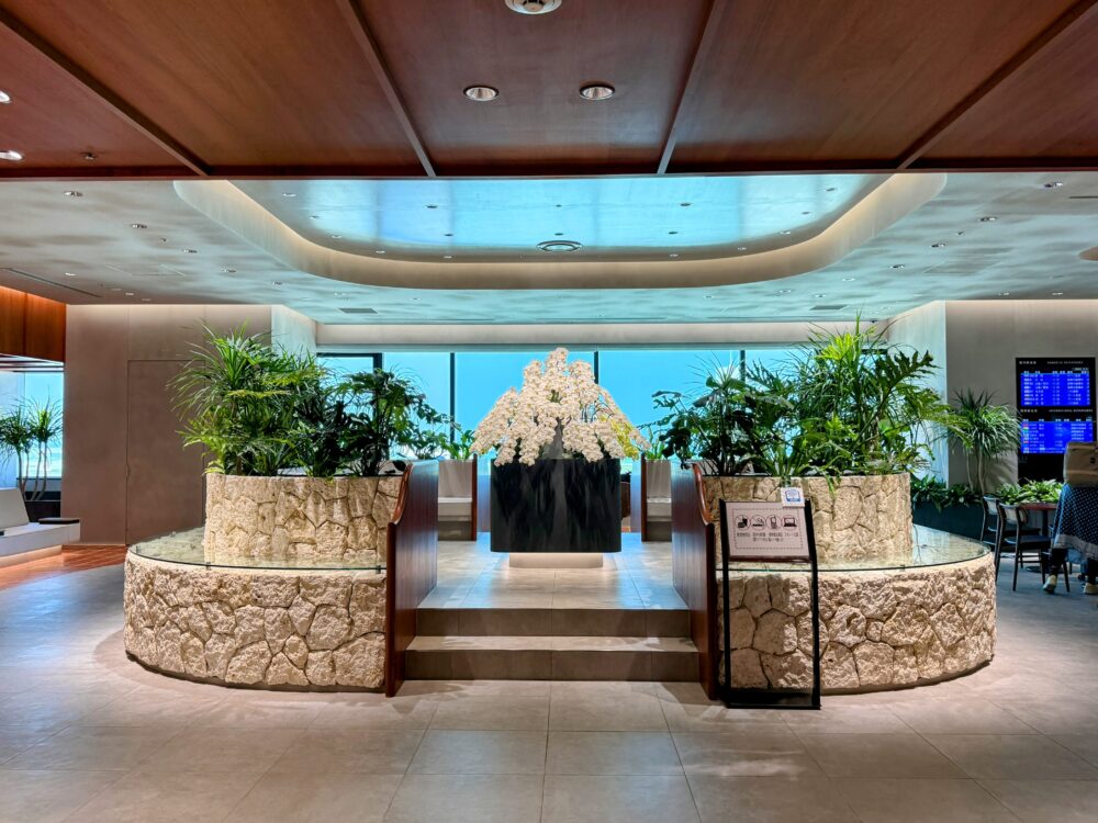 那覇空港カードラウンジ「LOUNGE HANA」のエントランスに設置された琉球石灰岩の円形花壇と白い胡蝶蘭の装花