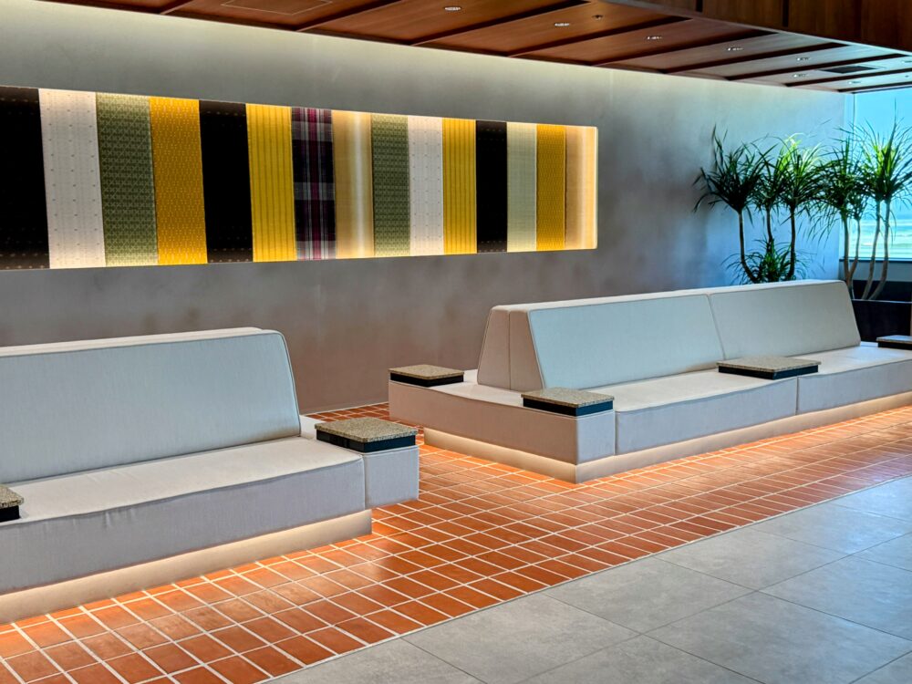 那覇空港カードラウンジ「LOUNGE HANA」のリニューアルされた白いソファと琉球模様の壁面アート