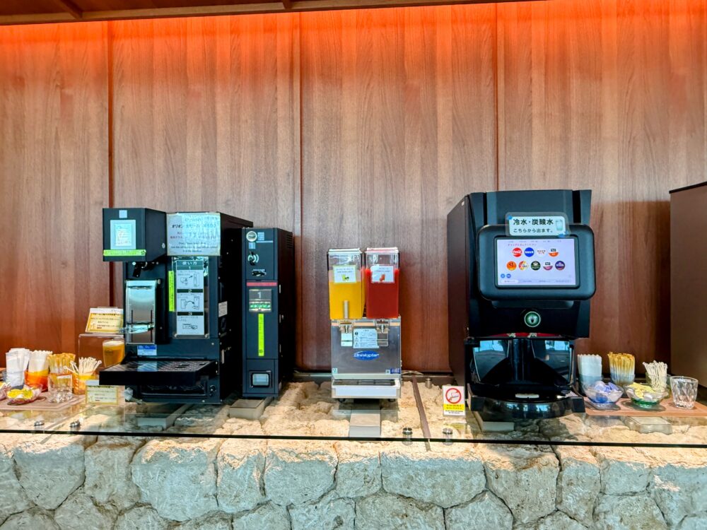 那覇空港カードラウンジ「LOUNGE HANA」のドリンクコーナーにあるオリオンビールサーバー・ジュースディスペンサー・炭酸水サーバーが並ぶセルフサービスエリア