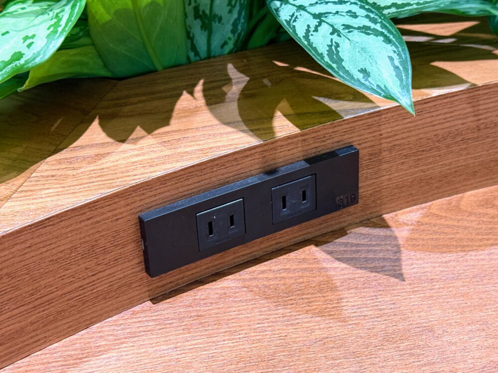 那覇空港カードラウンジ「LOUNGE HANA」のテーブル側面に埋め込まれたブラックの電源コンセント2口