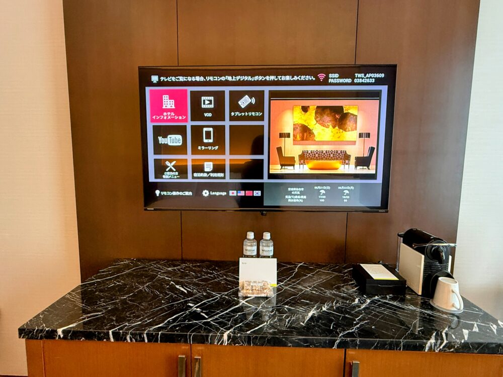 客室の壁掛けテレビのホテルインフォメーション画面と、ウェスティンの水・ネスプレッソマシン