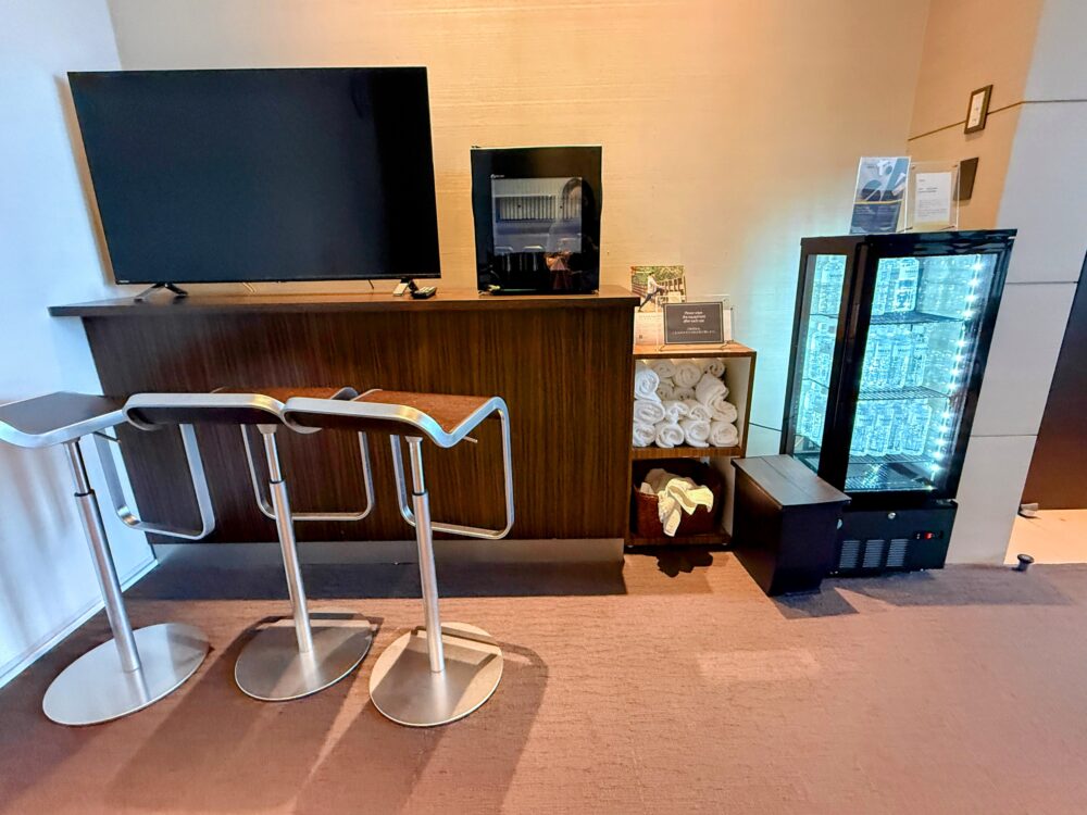 ウェスティンホテル仙台のフィットネスジムのドリンクコーナー。テレビ・タオル・冷蔵庫・ハイスツール
