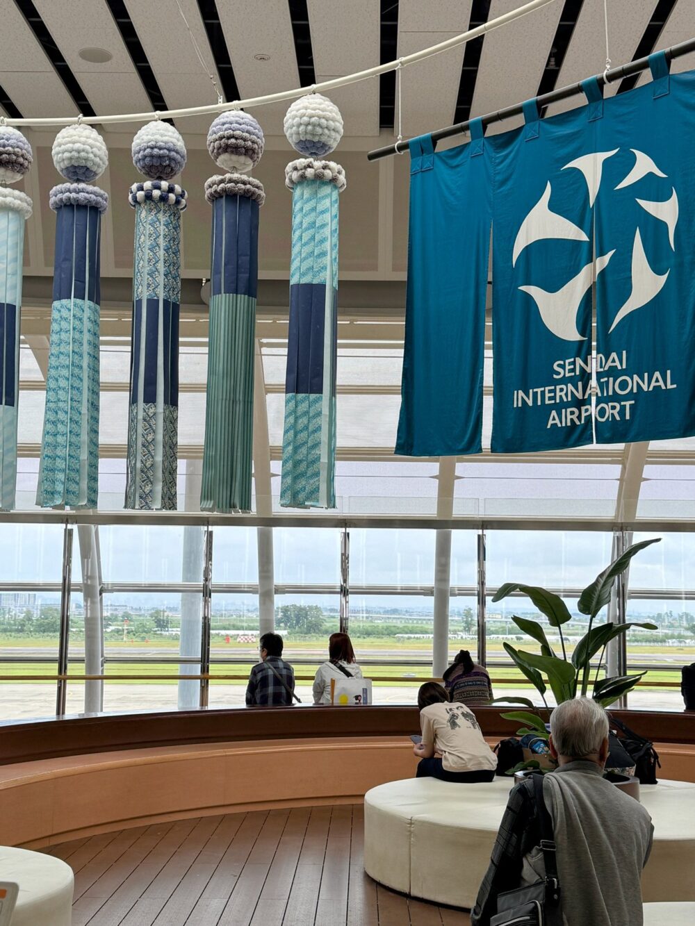仙台空港2階の出発ロビー。仙台らしい七夕飾りとSENDAI INTERNATIONAL AIRPORTの暖簾、窓の外には滑走路