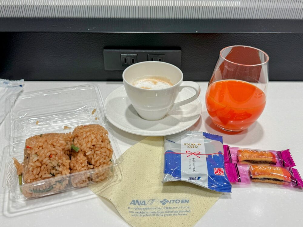 仙台空港ANAラウンジでのお盆。カフェラテ・トマトジュース・おにぎり・ANAオリジナルおつまみ・おかき