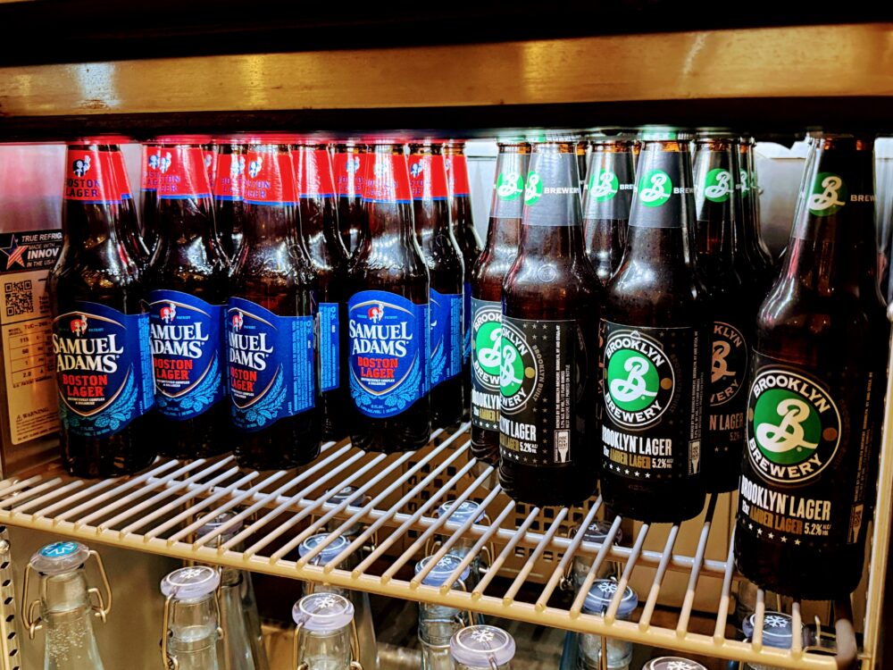 ビジネスクラスラウンジの冷蔵庫。Samuel Adams Boston LagerとBrooklyn Brewery Brooklyn Lagerのビンが並んでいます。