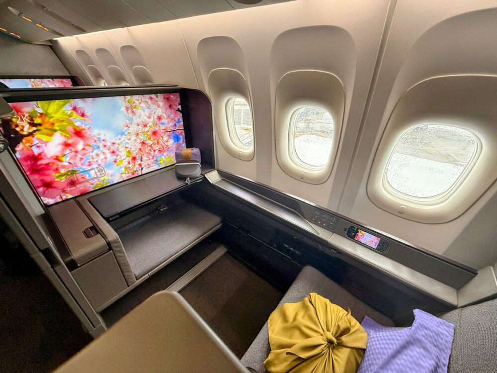 ANA NH109便ファーストクラスのシート。大型モニターに桜の映像が映し出され、窓から外の光が差し込む個室感のある上質な空間です。