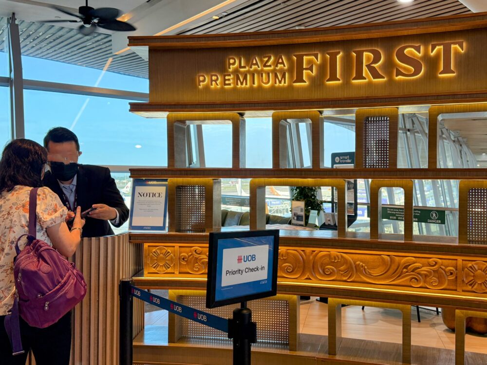 「Plaza Premium First」の豪華な木製レセプションカウンターと案内板
