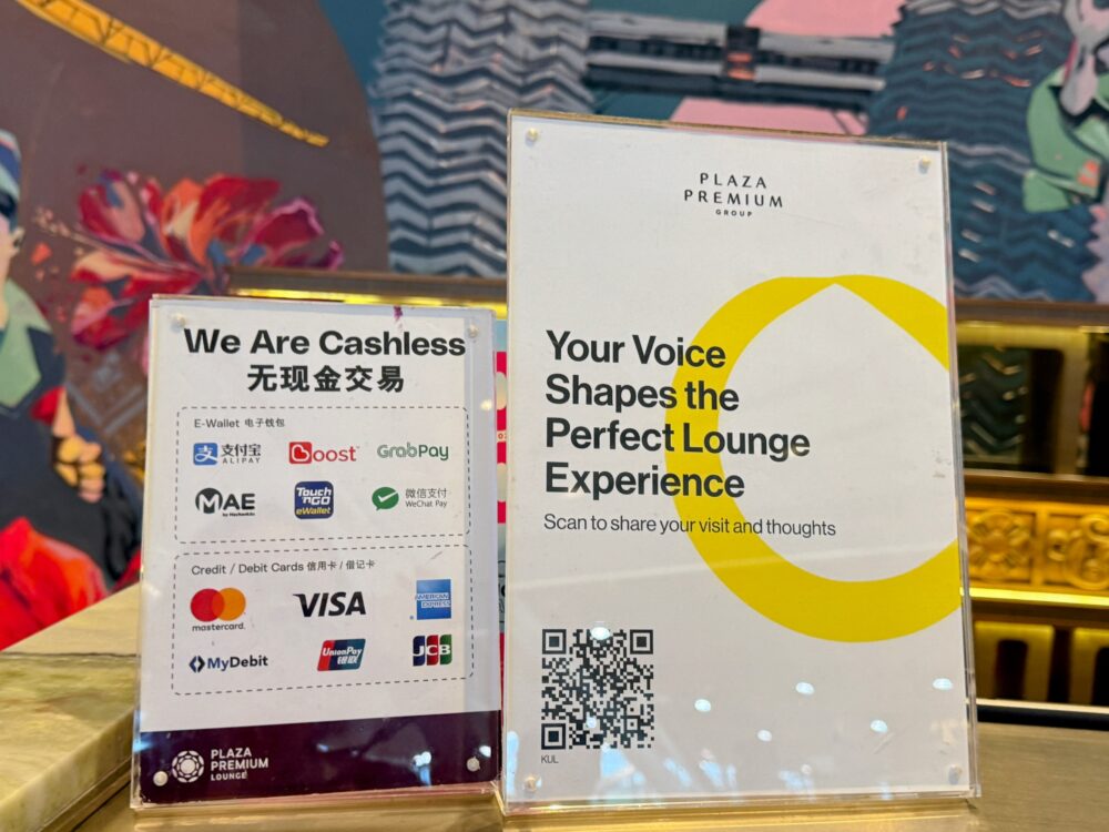 キャッシュレス決済対応の電子マネーやクレジットカードのブランド一覧が示された案内板とアンケート用QRコード
