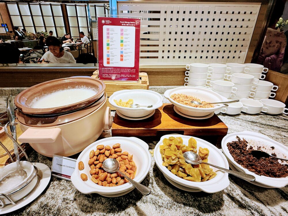 おかゆと、ピーナッツや漬物、乾燥肉などのトッピング用具材が並ぶビュッフェコーナー