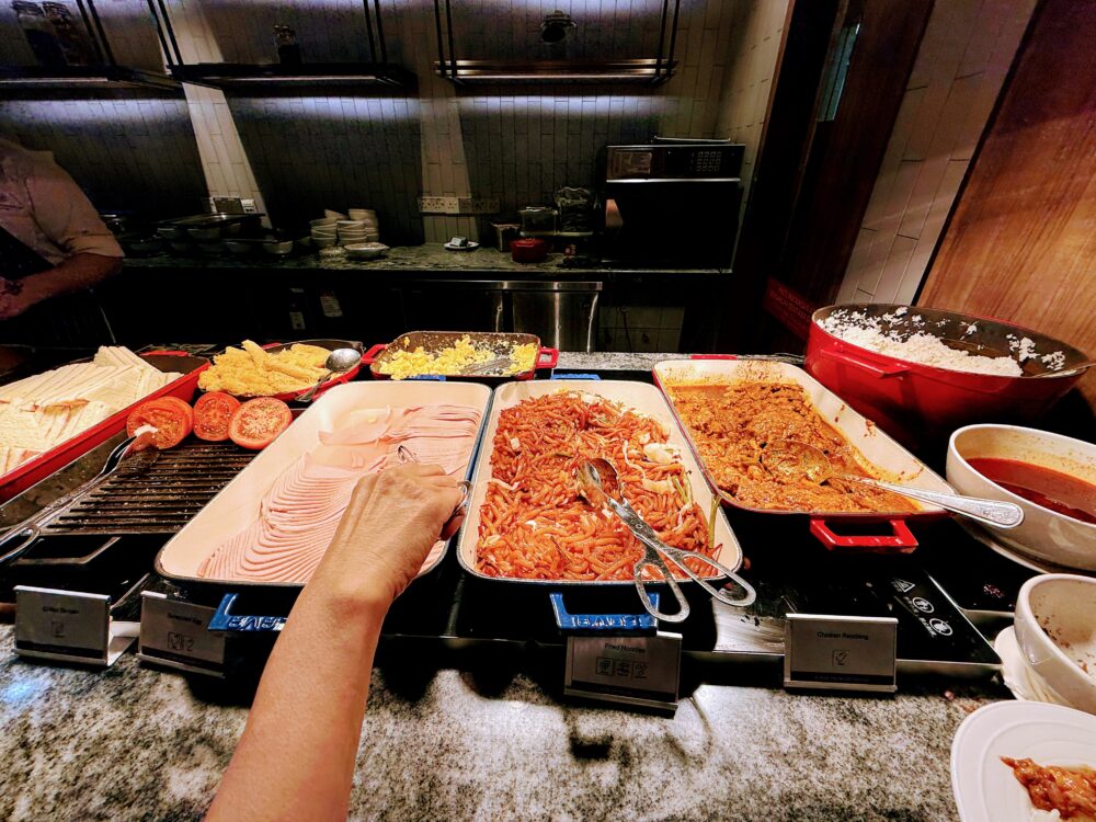 プラザプレミアムラウンジのビュッフェカウンターにある温かい料理の数々。ハム、麺料理、チキンレンダンなど