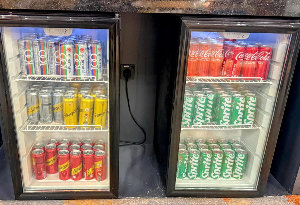 缶の炭酸飲料やソフトドリンクがきれいに陳列されたラウンジ内の冷蔵ケース