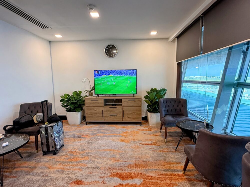 テレビモニターや観葉植物が配置された、落ち着いた色合いのラウンジ内のラウンジスペース