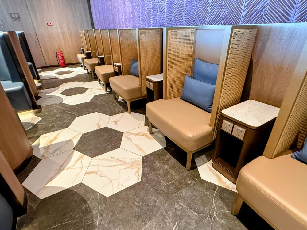 「GLOBAL LOUNGE」内のパーソナルソファ席エリアの様子。大理石調とダークブラウンの幾何学模様が施された床に、ラタン調の仕切りがあるプライベート感の高いソファ席が連なっている。