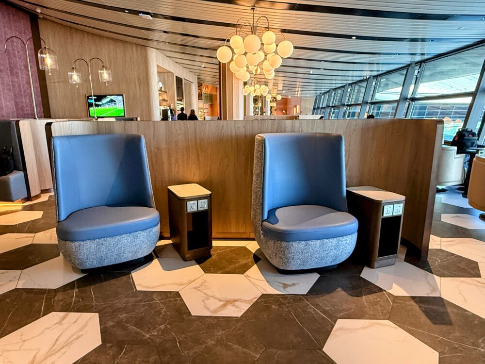 「GLOBAL LOUNGE」内の仕切り付きソファ席。青いハイバックの1人掛けチェアが木製のパーテーションに沿って並び、それぞれのチェアの脇には電源ポート付きの小さなサイドテーブルが置かれている。