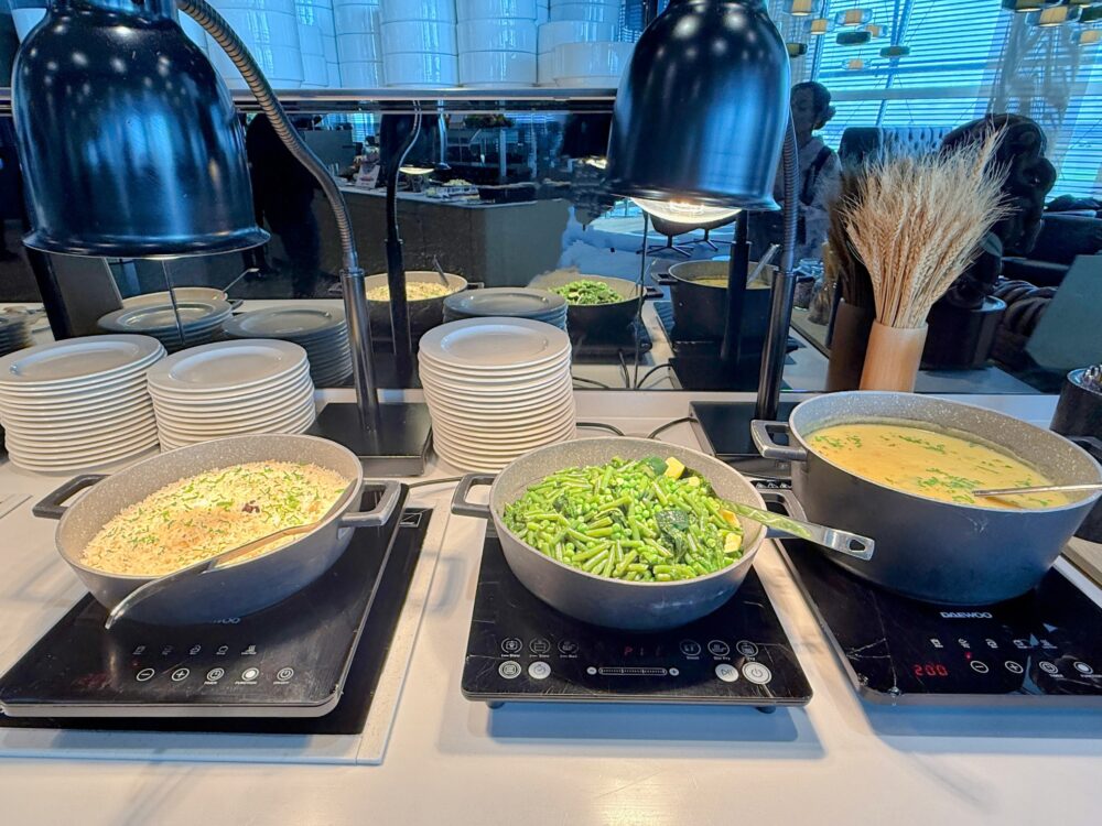 ルフトハンザラウンジの温かい料理が並ぶホットビュッフェカウンター。ピラフや温野菜、スープなどが保温されている。