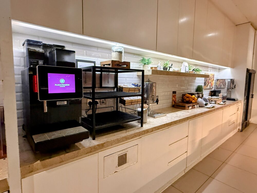 プラザプレミアムラウンジのドリンク・セルフサービスカウンター。タッチパネル式のコーヒーマシンやポット、食器類が整理されている。
