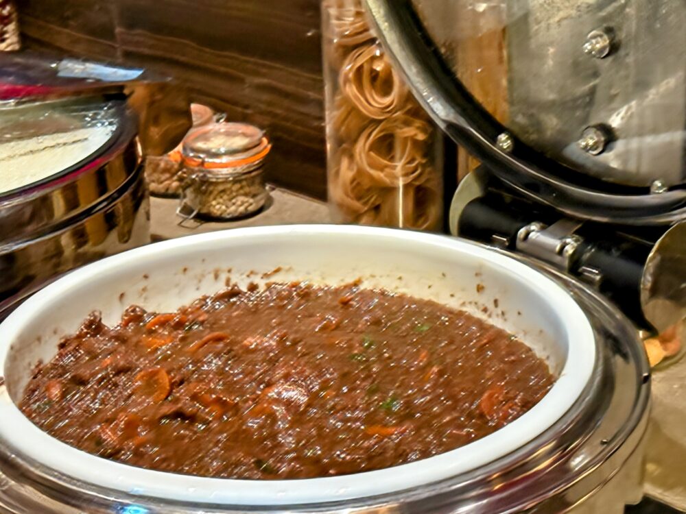 エアカナダ メープルリーフラウンジのホットミール。深めの容器に、人参などの野菜やお肉が入った濃厚なビーフシチュー(または煮込み料理)がたっぷり用意されている様子。
