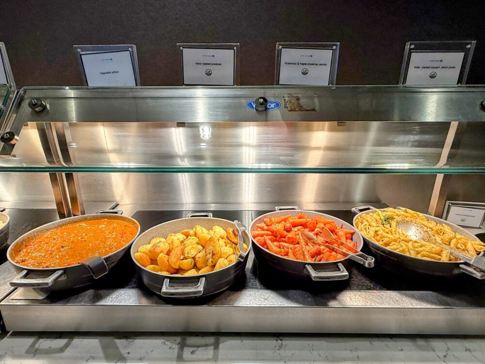 ユナイテッドクラブの、温かい料理が並ぶホットミールコーナー(スープ、ポテト、ローストキャロット、ペンネパスタなど)。