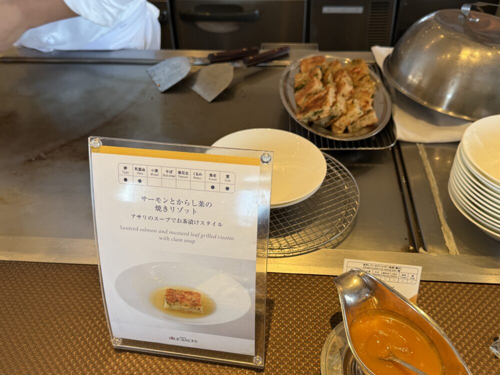 サーモンとからし菜の焼きリゾットの案内板。アサリのスープでお茶漬けスタイル