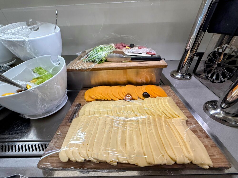 ラップに包まれた数種類のスライスチーズと、新鮮なサラダ用の野菜が置かれたカウンター。